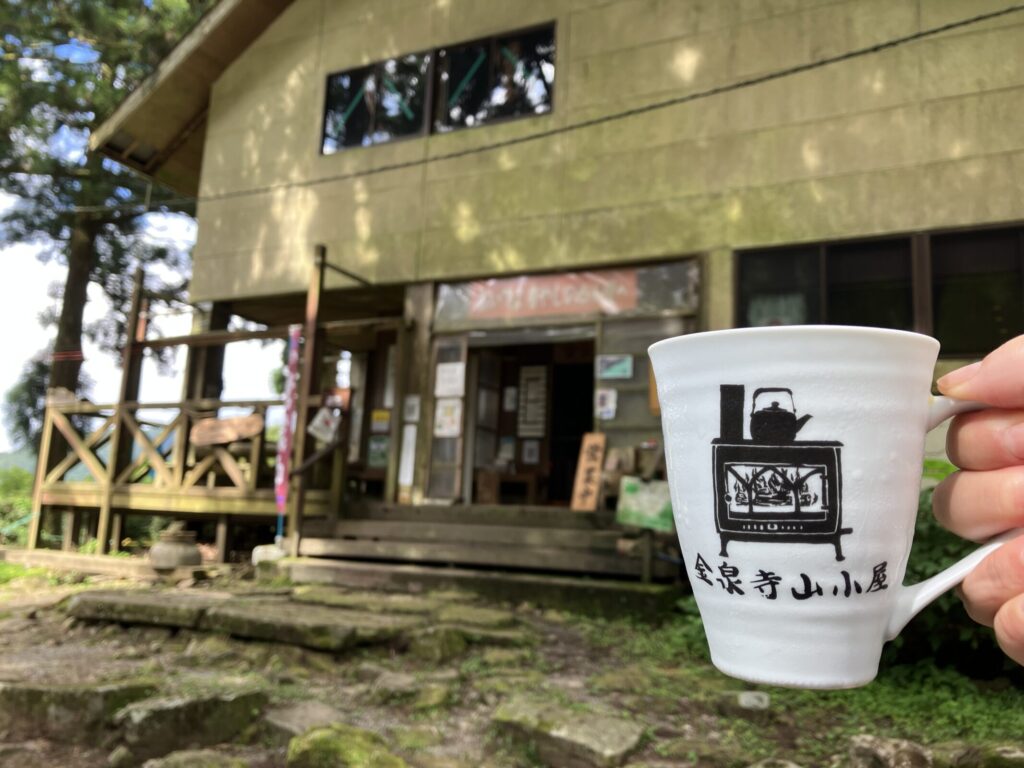 金泉寺山小屋の前で手にしたアイスコーヒーのカップ（山小屋のロゴ入り）